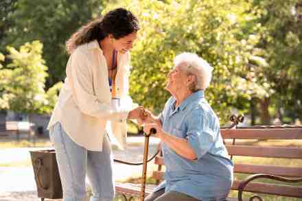 Alte Dame auf Bank und Pflegerin
